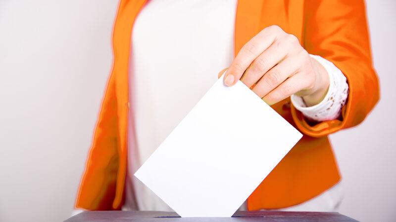 Person wählt an Wahlurne, übt Recht auf Wahlen in der Demokratie aus